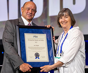 Tom Toner (left) presented the Distinguished Member and Fellow Award to Margaret Mumford (right), on behalf of her late husband, Ian Bakshi.